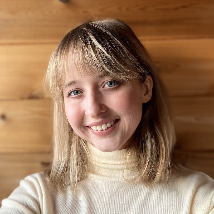 Maddy is a white woman in her late twenties with shoulder-length blonde hair and bangs. She is smiling and wears a pale-yellow turtleneck sweater.